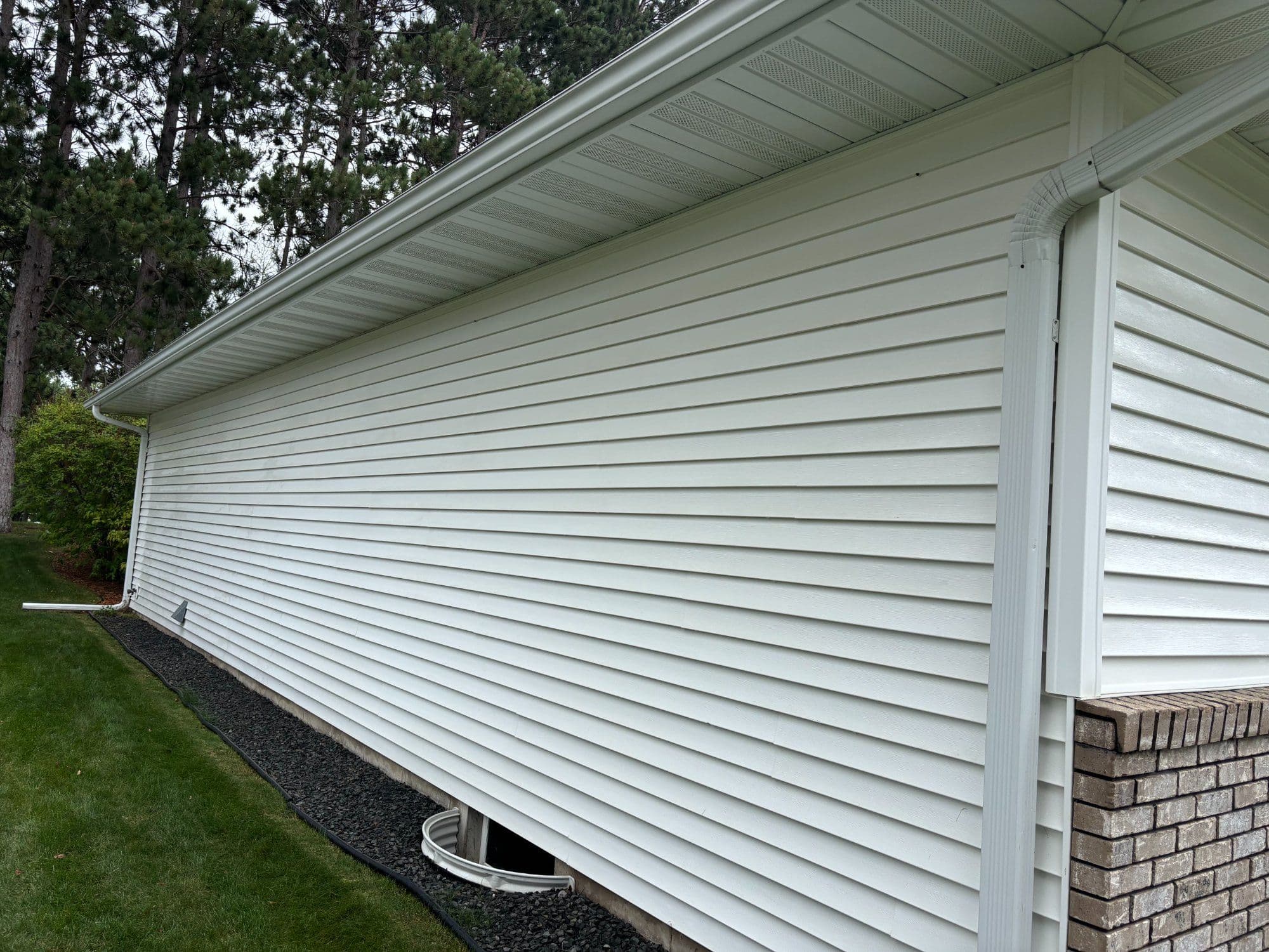 Side view of a house featuring white vinyl siding and a landscaped yard.