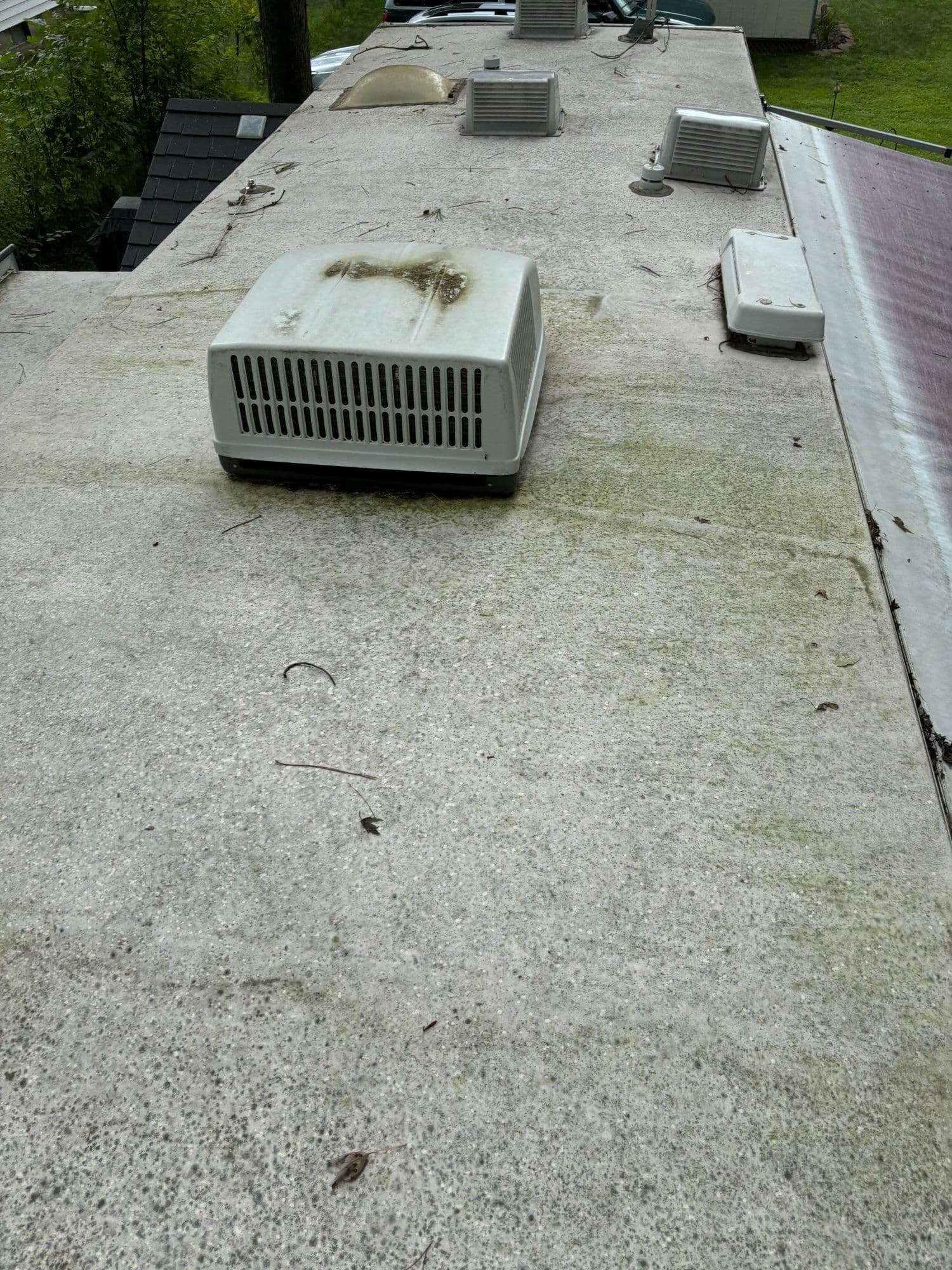 Roof equipment on a flat surface with moss, showcasing maintenance needs.